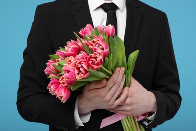 Photo of Man with beautiful bouquet on light blue background, closeup