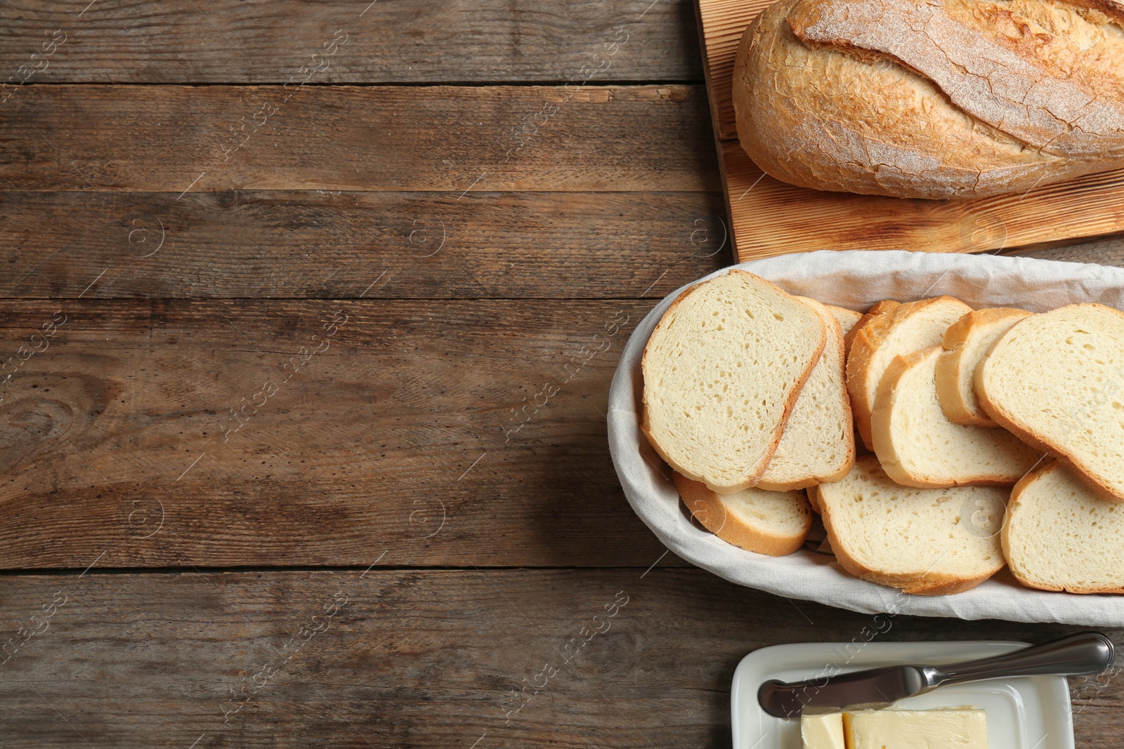 Photo of Tasty fresh bread with butter on wooden table, flat lay. Space for text