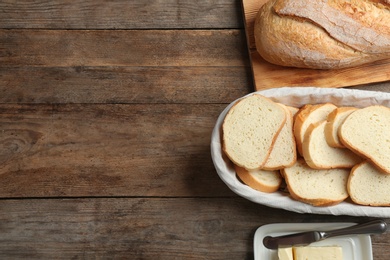 Photo of Tasty fresh bread with butter on wooden table, flat lay. Space for text