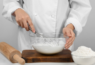 Woman whipping egg whites at wooden table, closeup. Baking pie