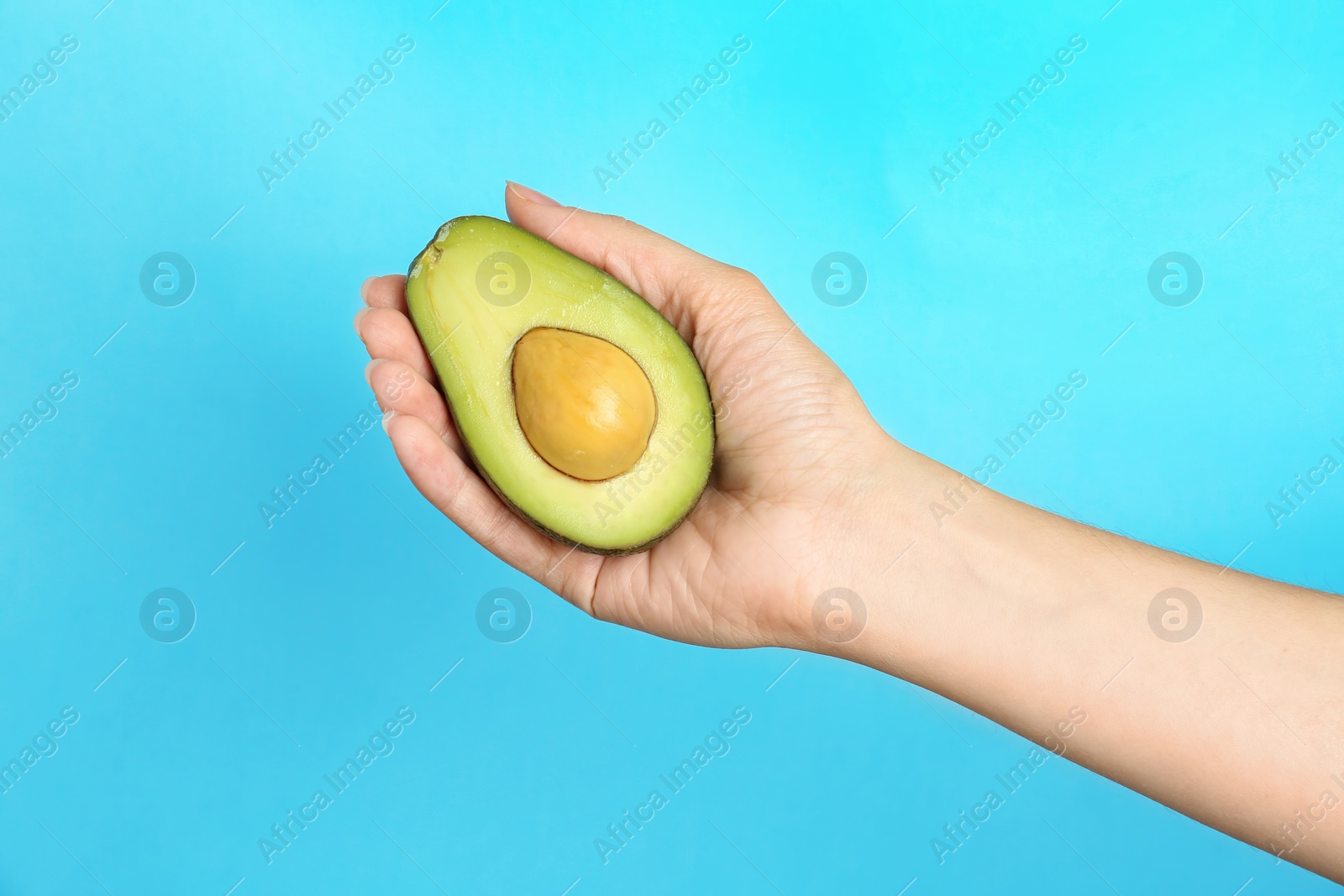 Photo of Woman holding ripe cut avocado on color background