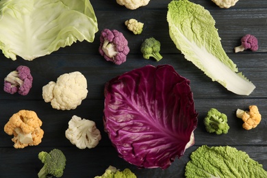 Photo of Fresh leaves of different cabbages on wooden table, top view. Healthy food