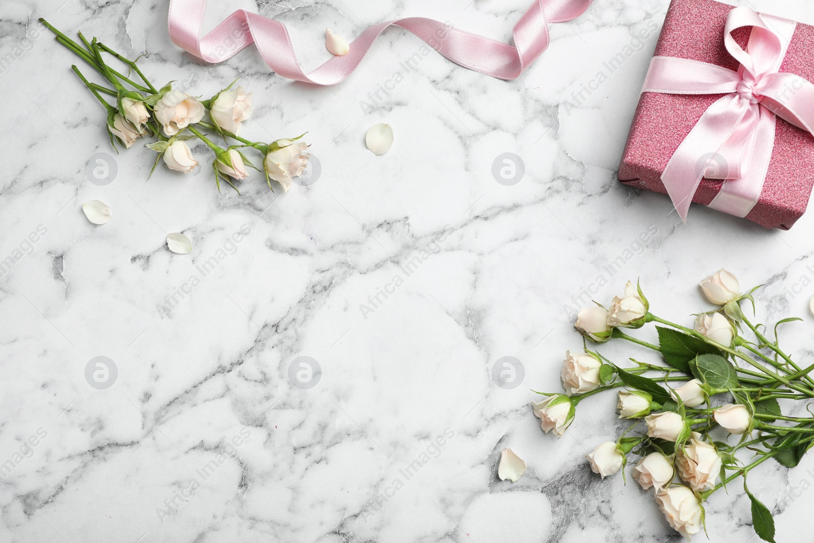 Photo of Flat lay composition with beautiful roses and gift box on marble background. Space for text