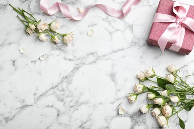 Photo of Flat lay composition with beautiful roses and gift box on marble background. Space for text