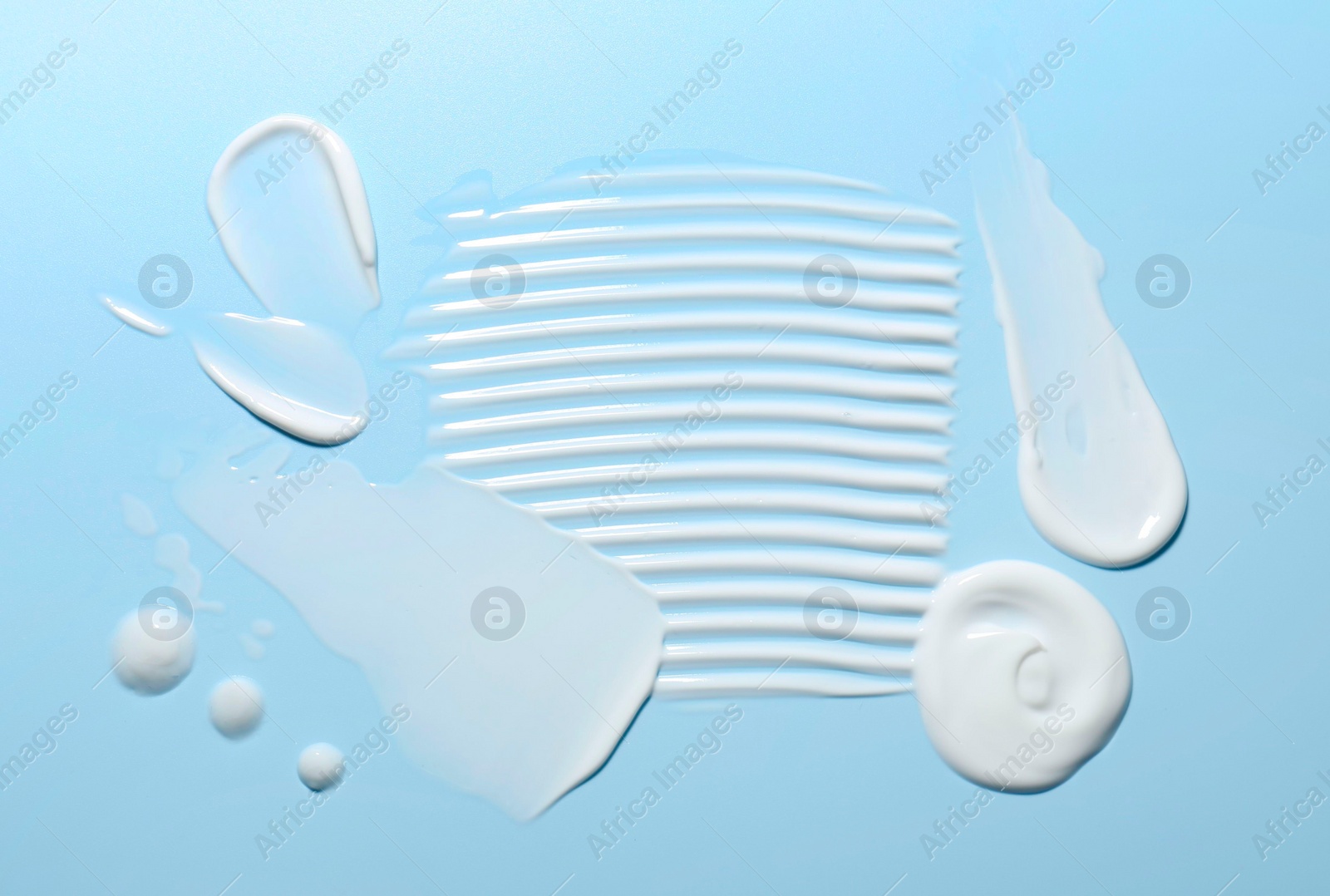 Photo of Samples of face cream on light blue background, top view