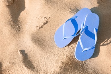 Stylish flip flops on beach, top view. Space for text