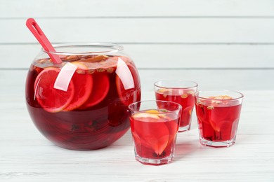 Photo of Glasses and bowl with aromatic punch drink on white wooden table