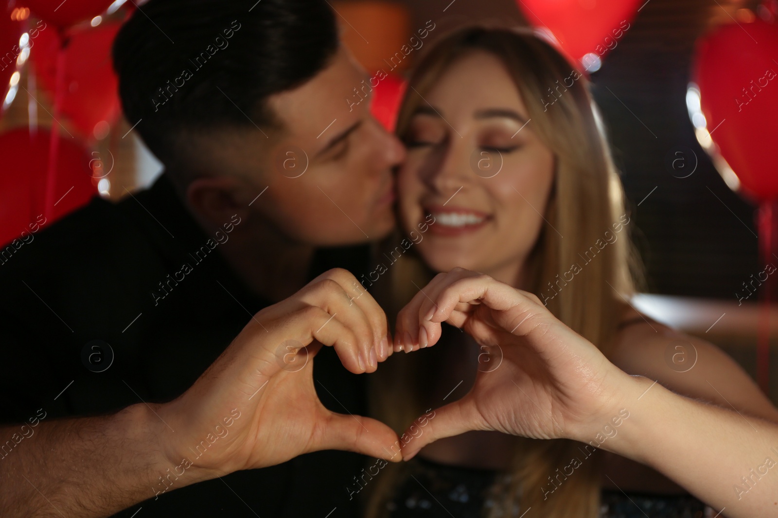 Photo of Lovely couple making heart with hands indoors. Valentine's day celebration