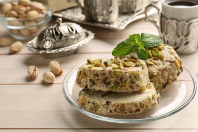 Photo of Tasty halva with pistachios and mint served on wooden table, closeup