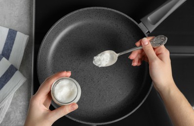 Photo of Woman cooking with coconut oil on induction stove, top view