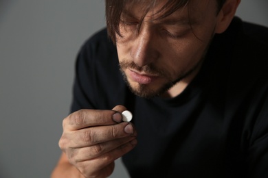 Photo of Young addicted man with drugs on grey background