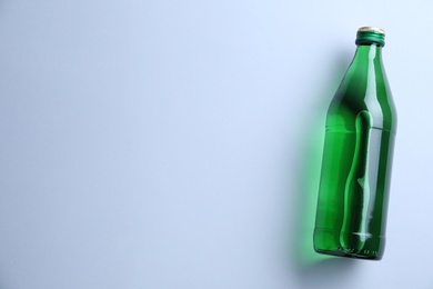 Glass bottle with water on white background, top view. Space for text