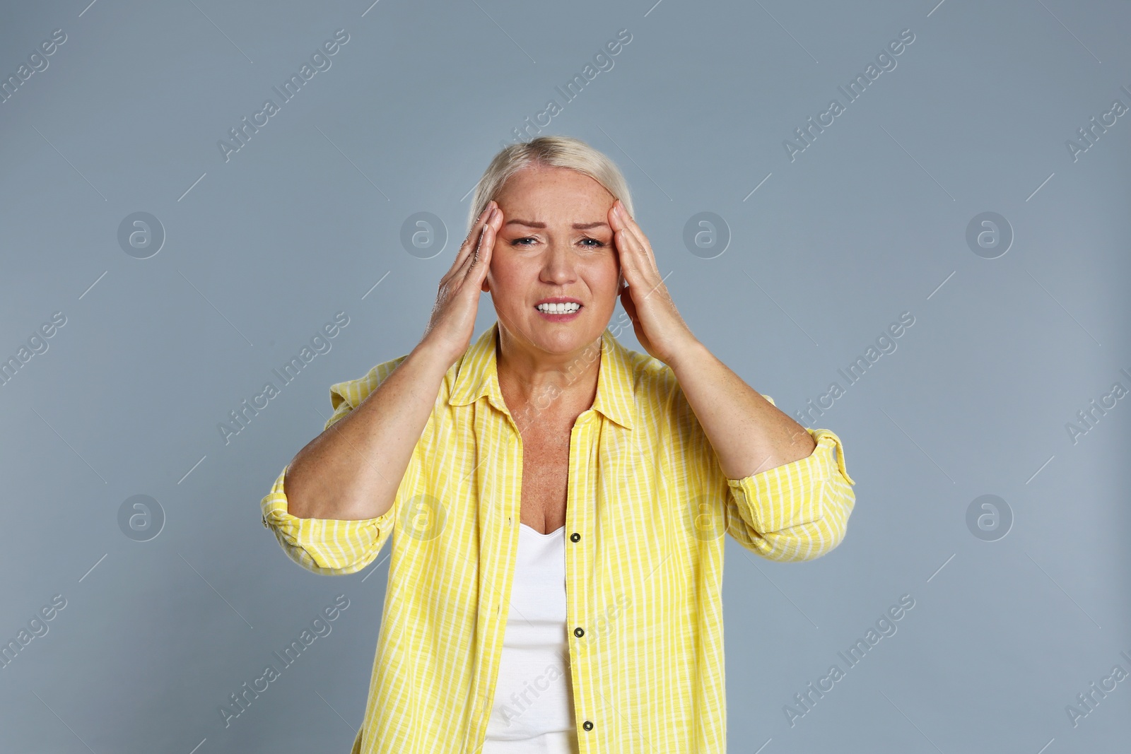 Image of Mature woman suffering from headache on grey background