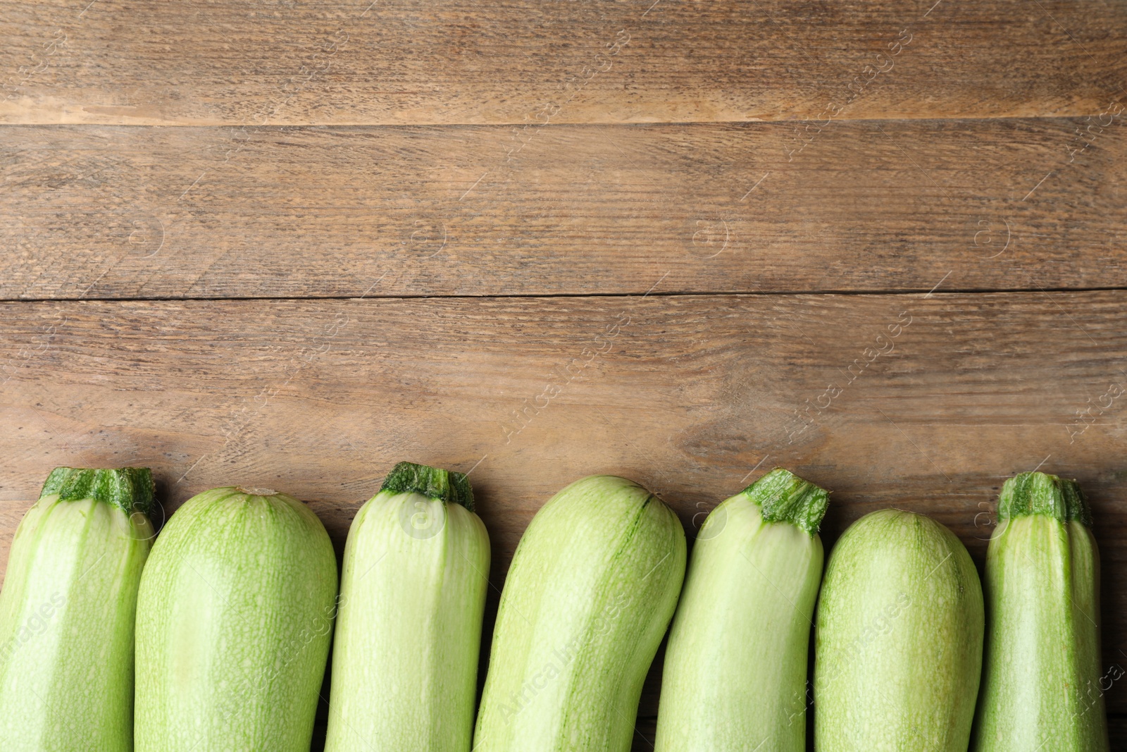 Photo of Raw green zucchinis on wooden table, flat lay. Space for text