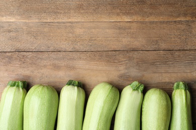Photo of Raw green zucchinis on wooden table, flat lay. Space for text