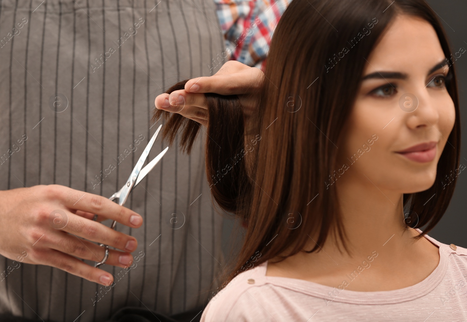 Photo of Barber making stylish haircut with professional scissors in beauty salon