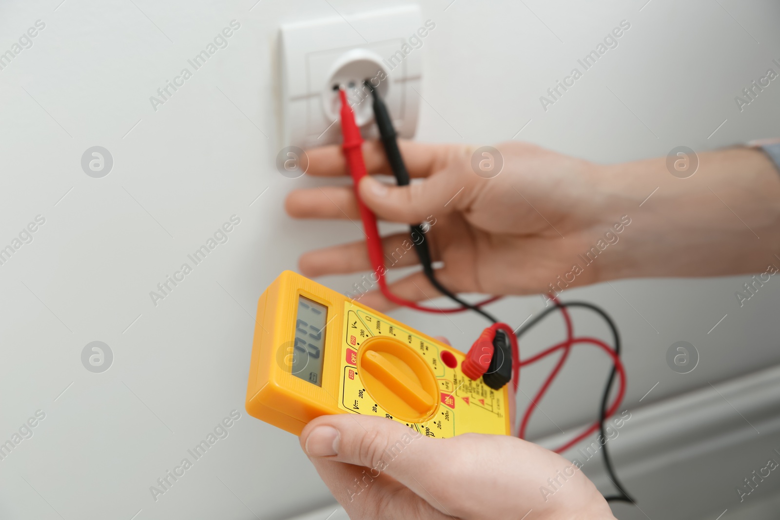 Photo of Electrician with tester checking voltage indoors, closeup