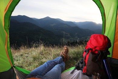 Photo of Woman resting inside of camping tent in mountains at sunset, closeup