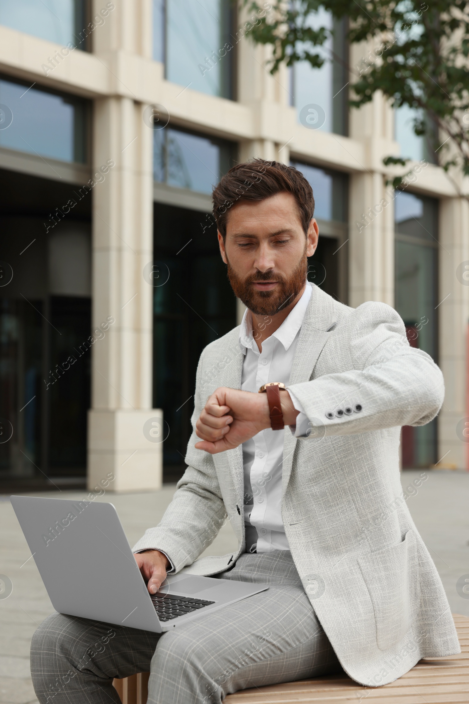 Photo of Handsome businessman with laptop on city street