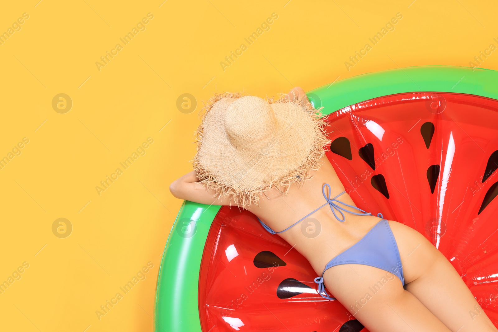 Photo of Sexy young woman with beautiful suntan and hat on inflatable mattress against orange background, top view. Space for text