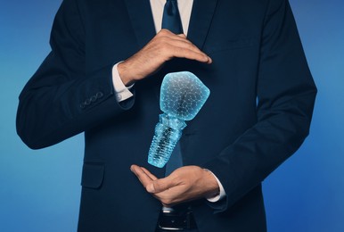 Man demonstrating virtual image of dental implant on blue background, closeup