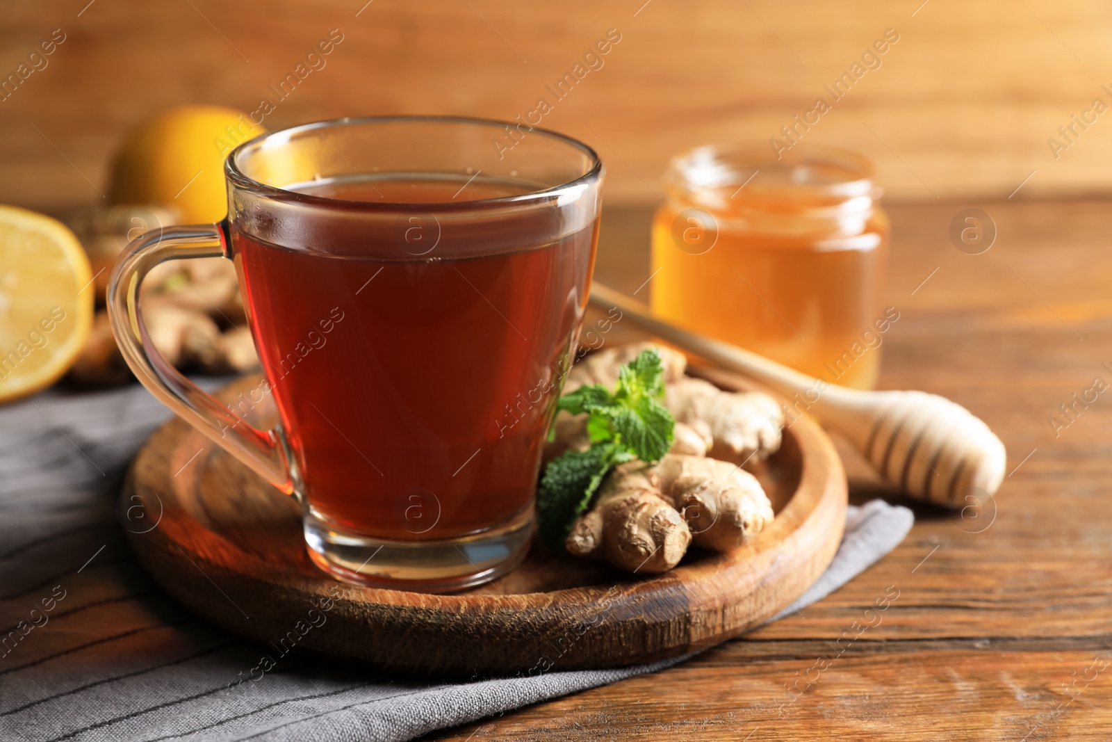 Photo of Cup of delicious ginger tea and ingredients on wooden table