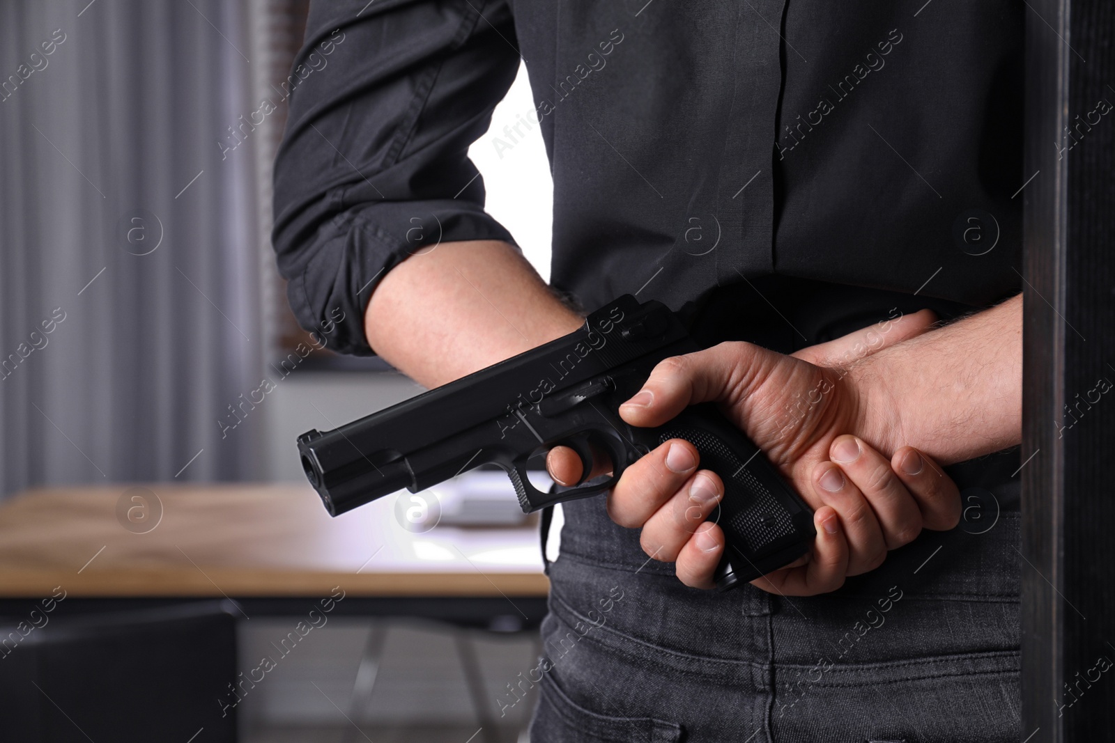Photo of Man holding gun indoors, closeup. Dangerous criminal