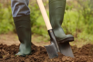 Photo of Worker digging soil with shovel outdoors, closeup. Gardening tool