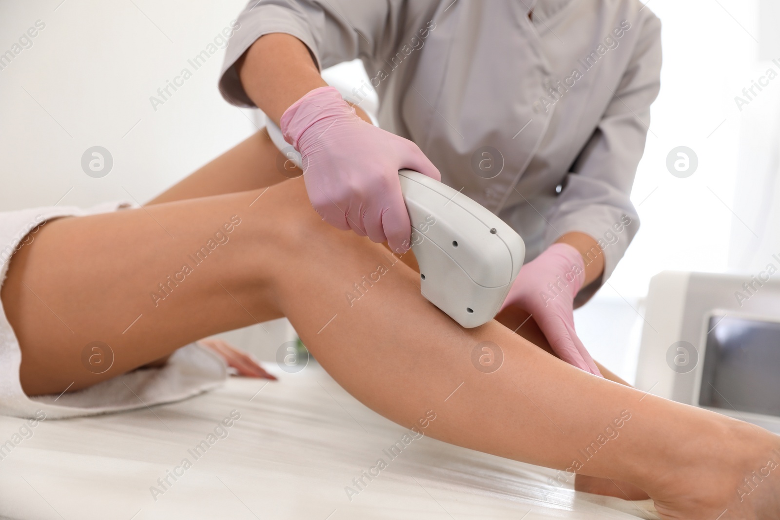 Photo of Young woman undergoing laser epilation procedure in beauty salon, closeup
