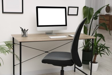 Stylish room interior with comfortable office chair, desk and houseplants