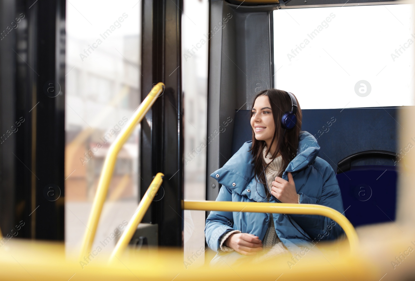 Photo of Young woman listening to music with headphones in public transport