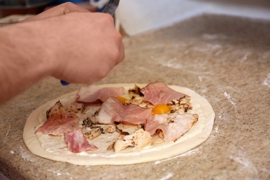Photo of Man preparing pizza at table, closeup. Oven recipe