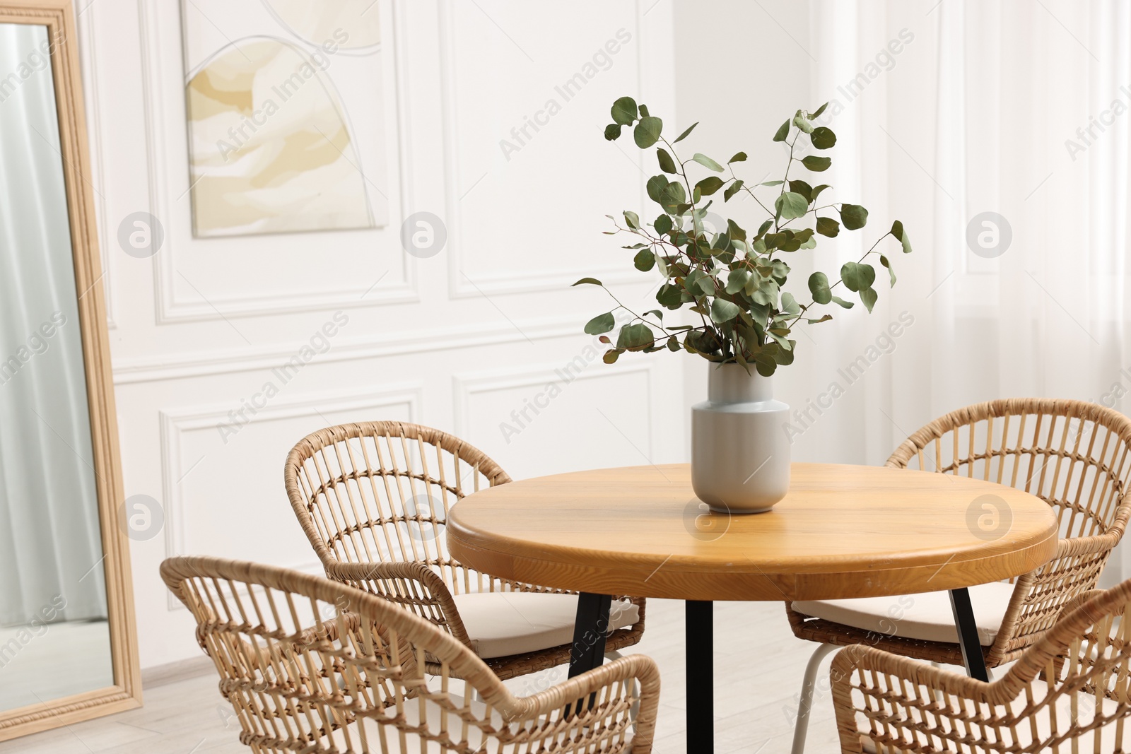 Photo of Dining room interior with comfortable furniture and eucalyptus branches