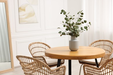 Dining room interior with comfortable furniture and eucalyptus branches