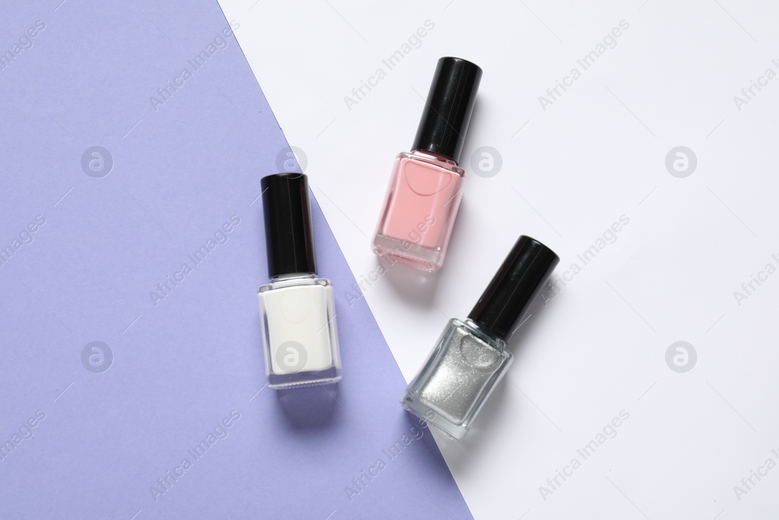 Photo of Nail polishes on color background, flat lay