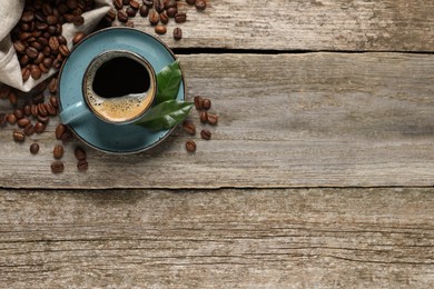 Photo of Cup of aromatic hot coffee and beans on wooden table, flat lay. Space for text