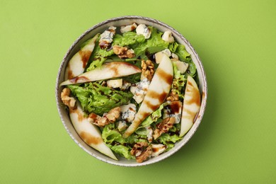 Delicious pear salad with sauce in bowl on green background, top view