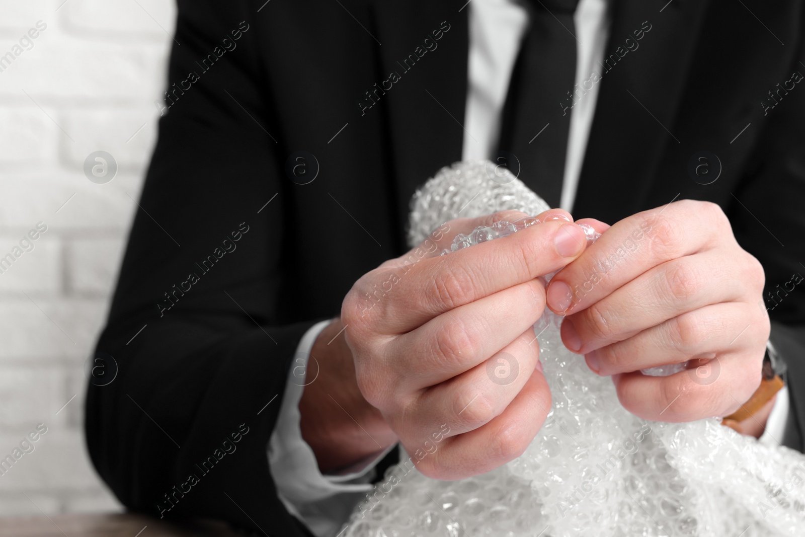 Photo of Stress relief. Businessman popping bubble wrap, closeup view. Space for text