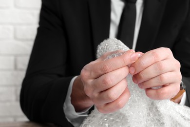 Stress relief. Businessman popping bubble wrap, closeup view. Space for text