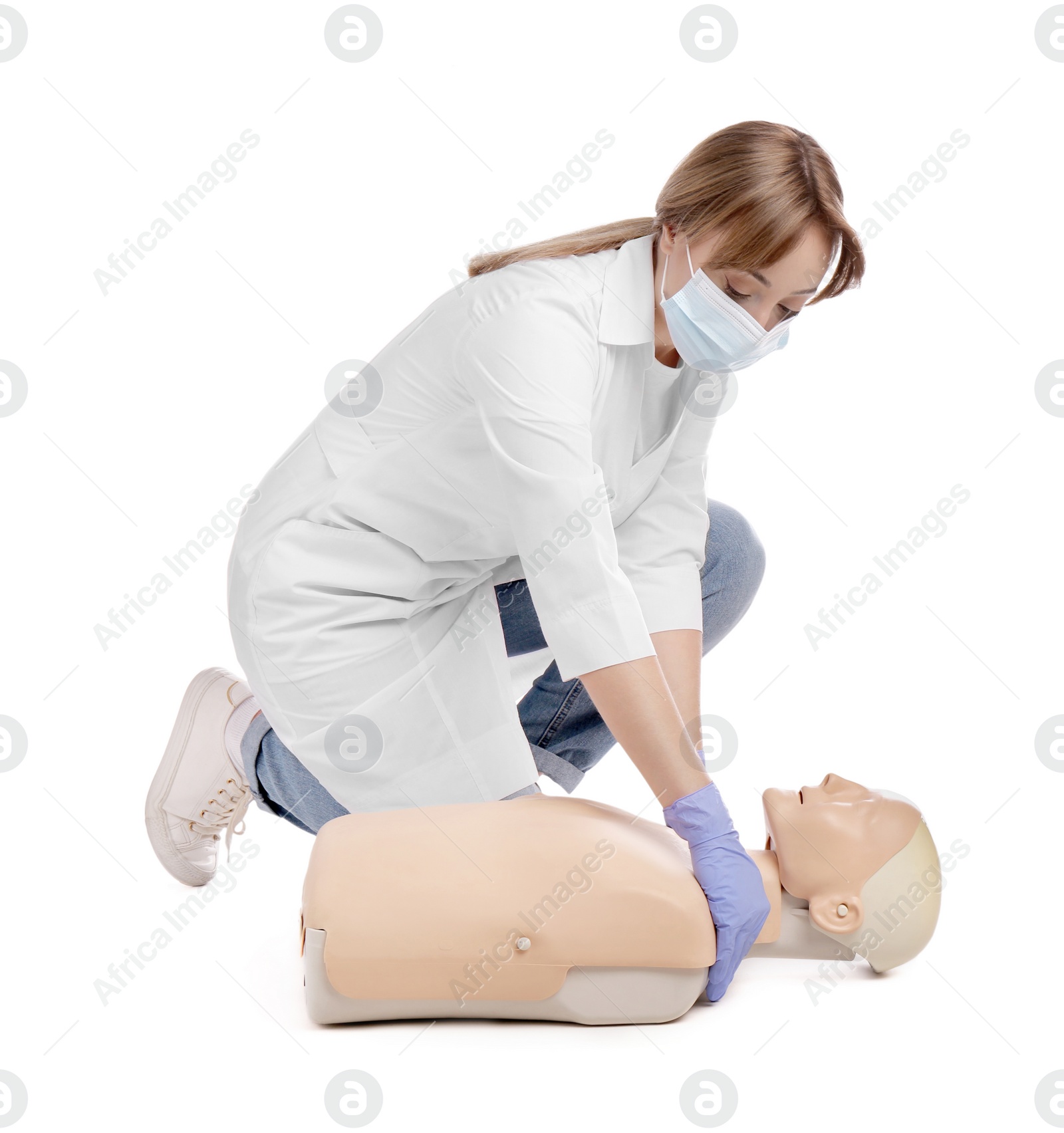 Photo of Doctor in uniform and protective mask practicing first aid on mannequin against white background