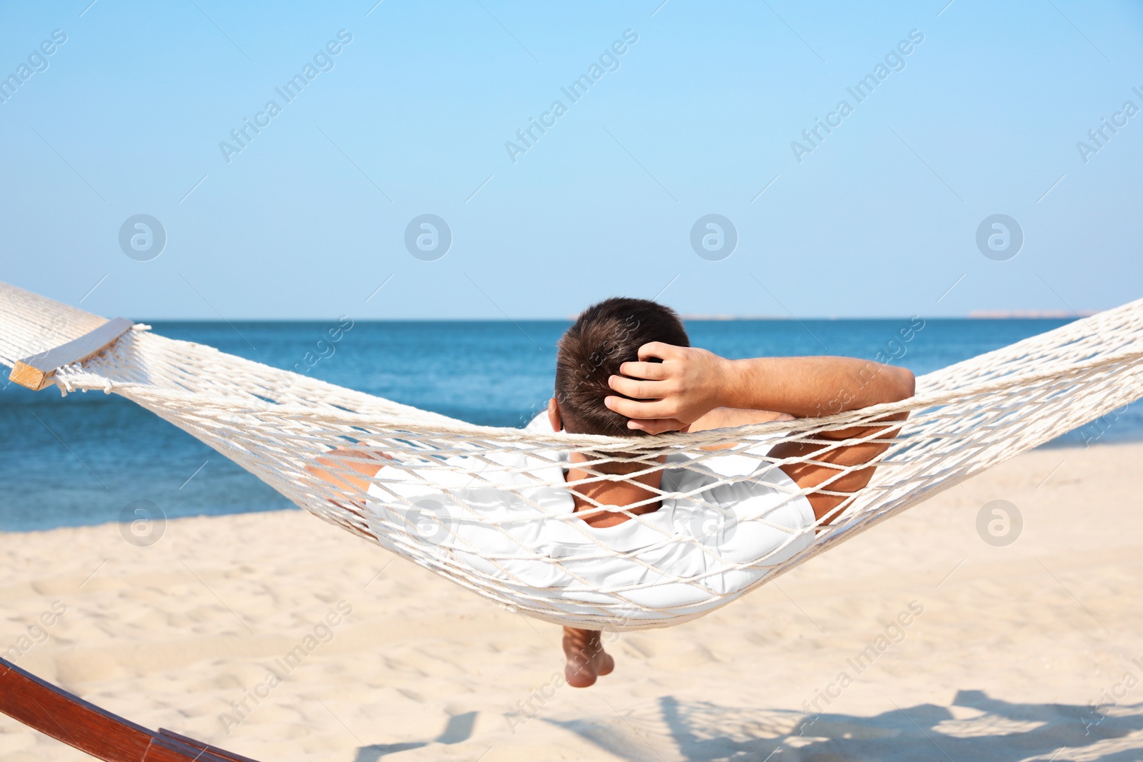 Photo of Young man relaxing in hammock on beach