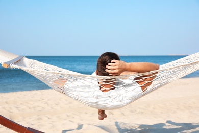 Photo of Young man relaxing in hammock on beach