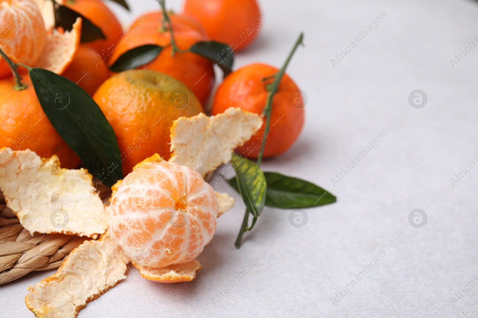 Photo of Many fresh ripe tangerines and leaves on white table, space for text