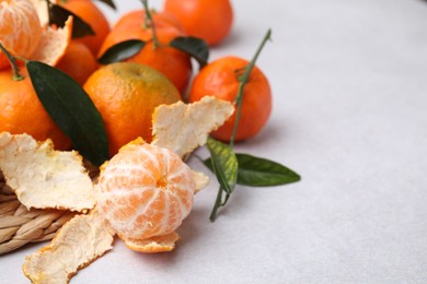 Photo of Many fresh ripe tangerines and leaves on white table, space for text