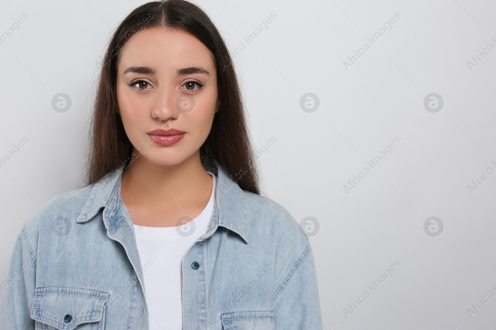 Photo of Portrait of beautiful young woman in jeans jacket on white background. Space for text