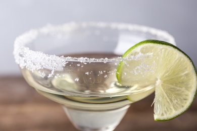 Glass of lemon drop martini cocktail with lime slice on table, closeup