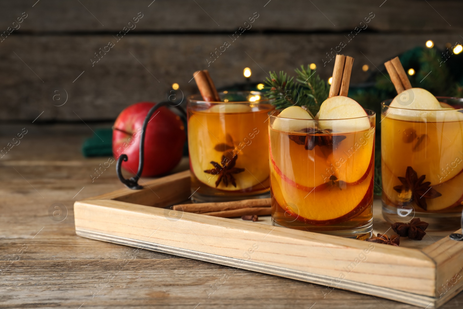 Photo of Hot mulled cider on wooden table, space for text