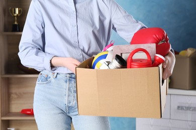 Photo of Woman holding box of unwanted stuff indoors, closeup
