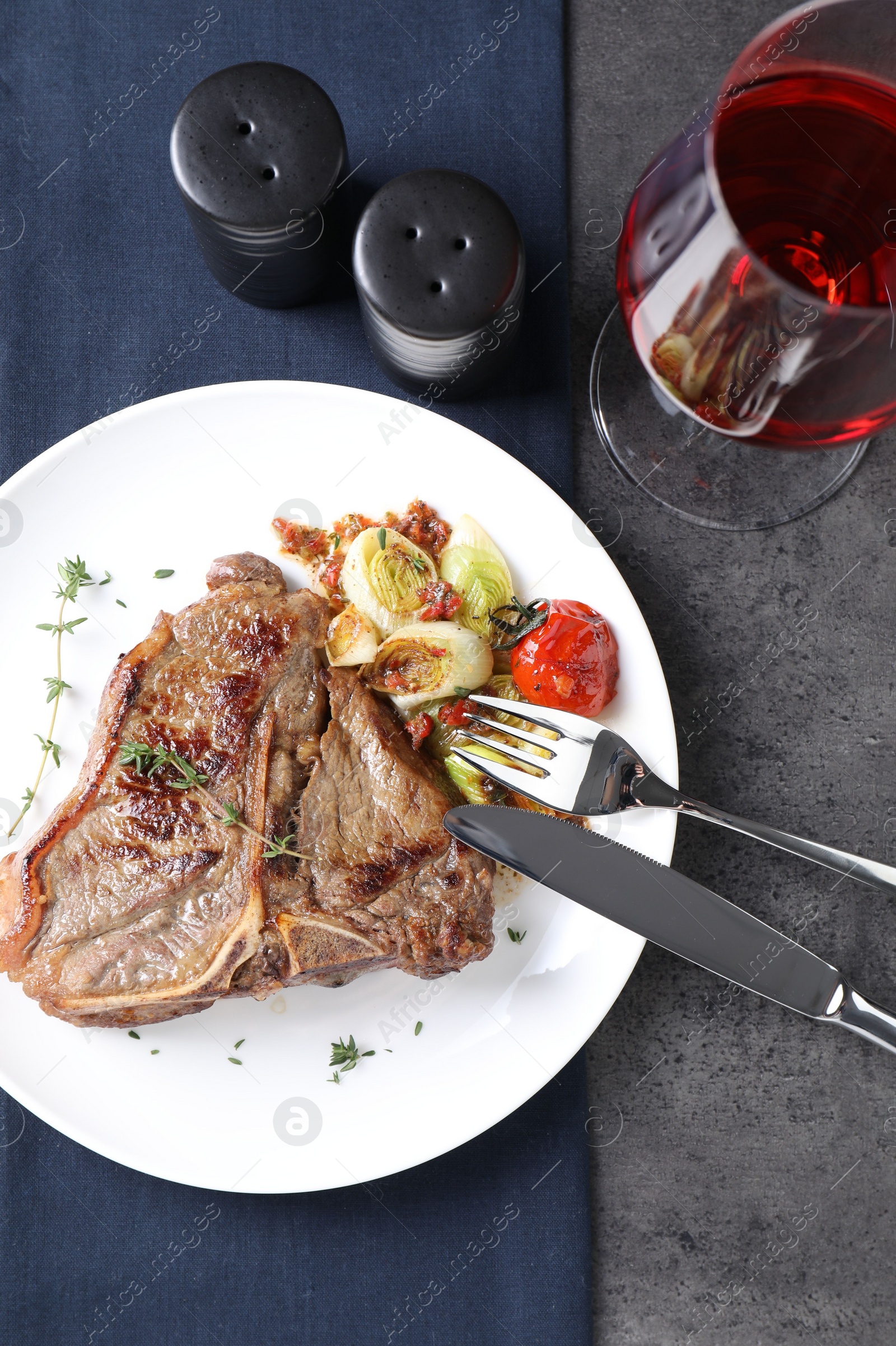 Photo of Delicious fried beef meat and vegetables served on grey table, top view