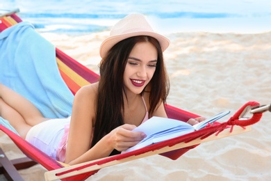 Young woman reading book in hammock at seaside